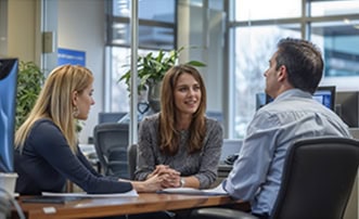 Bright Asian woman in business attire smiling during interview with two colleagues in a modern office setting.