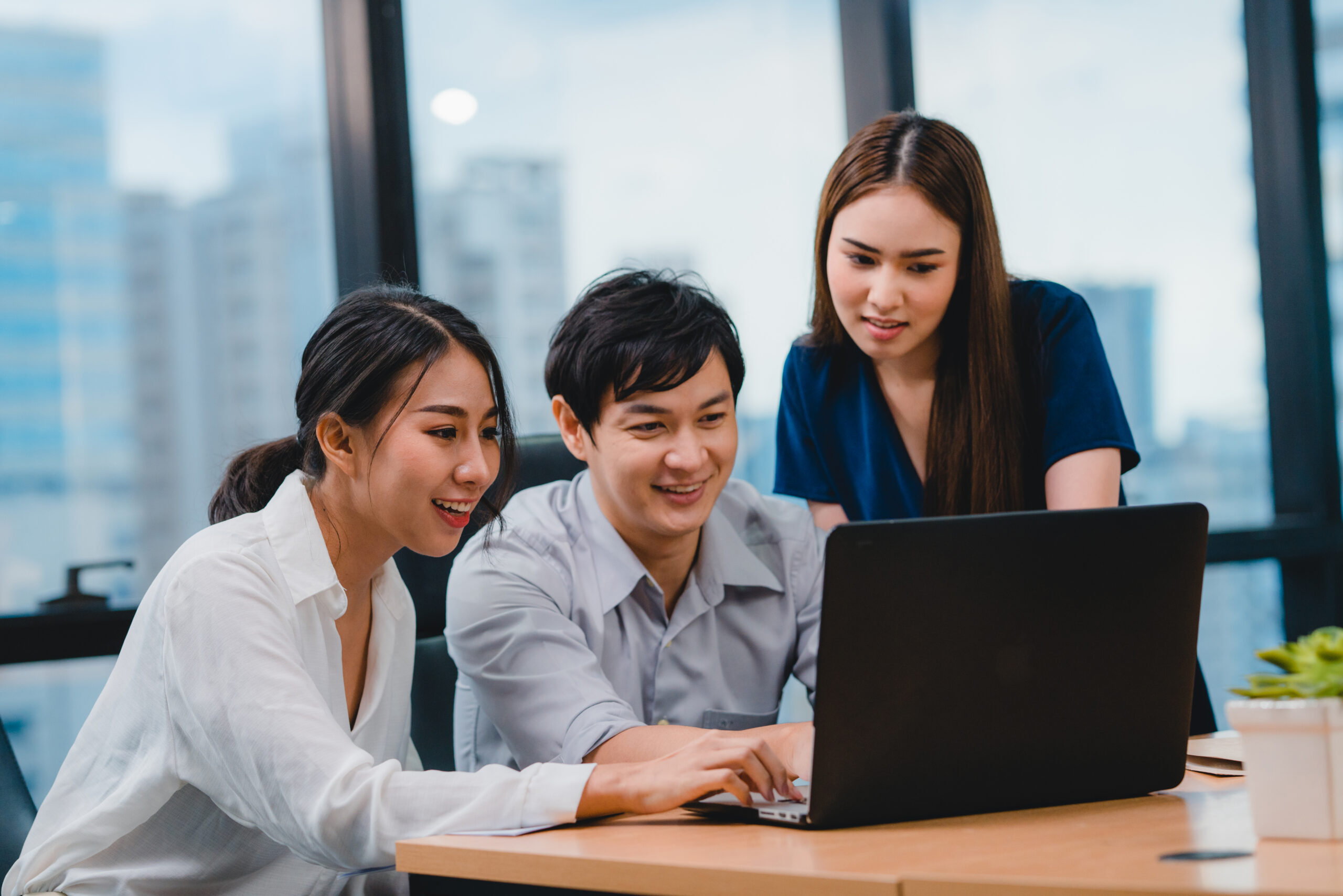 Team members reviewing work together around a laptop